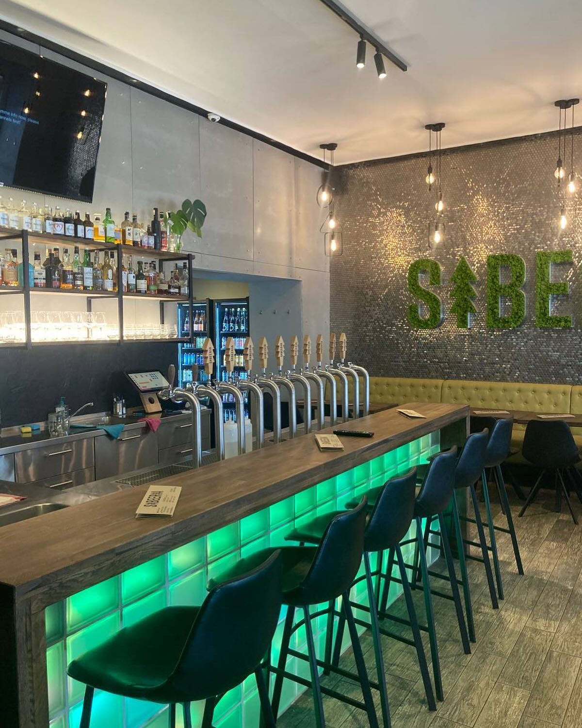 Interiér pražského TapRoomu se zeleným nápisem Sibeeria a žlutým posezením